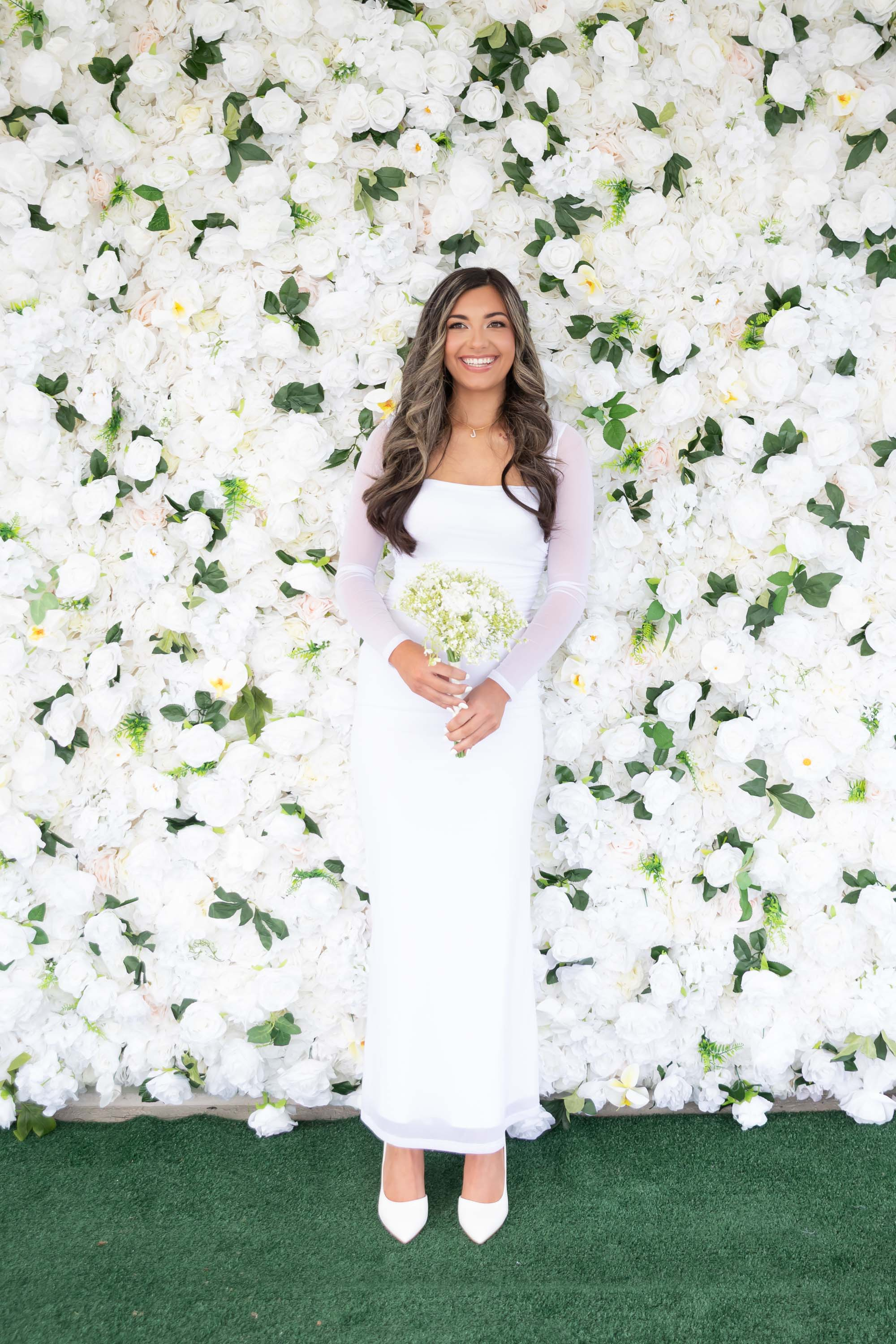 Nano Nuptials bride photographed in front of the floral wall